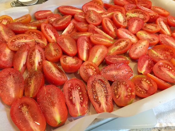 Sliced Roma Tomatoes on Parchment Paper Lined Cookie Sheet