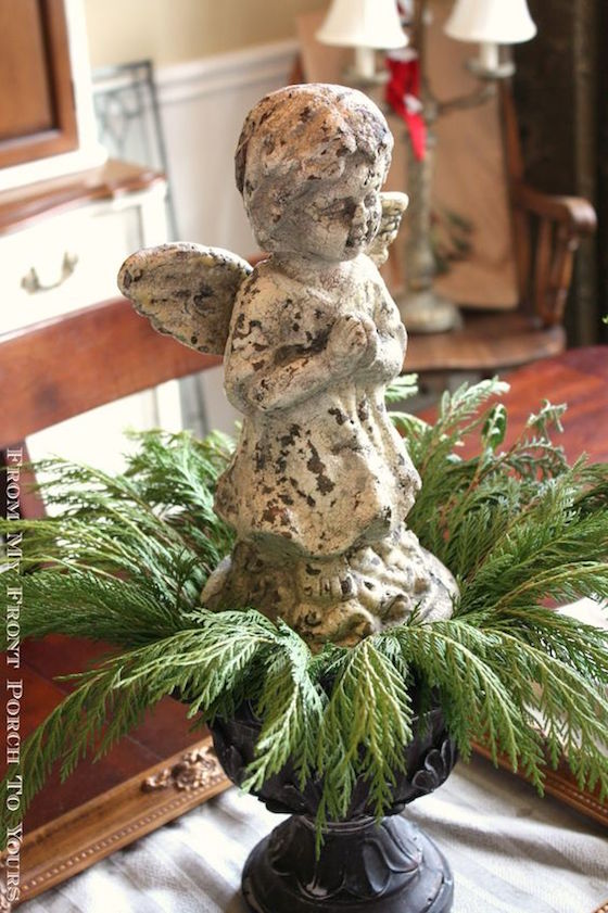 Add evergreen cuttings to an urn with a statue 