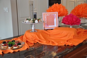 Use cake stands to add additional height. Tissue paper pompoms are an inexpensive and great way to add pops of color to your buffet.